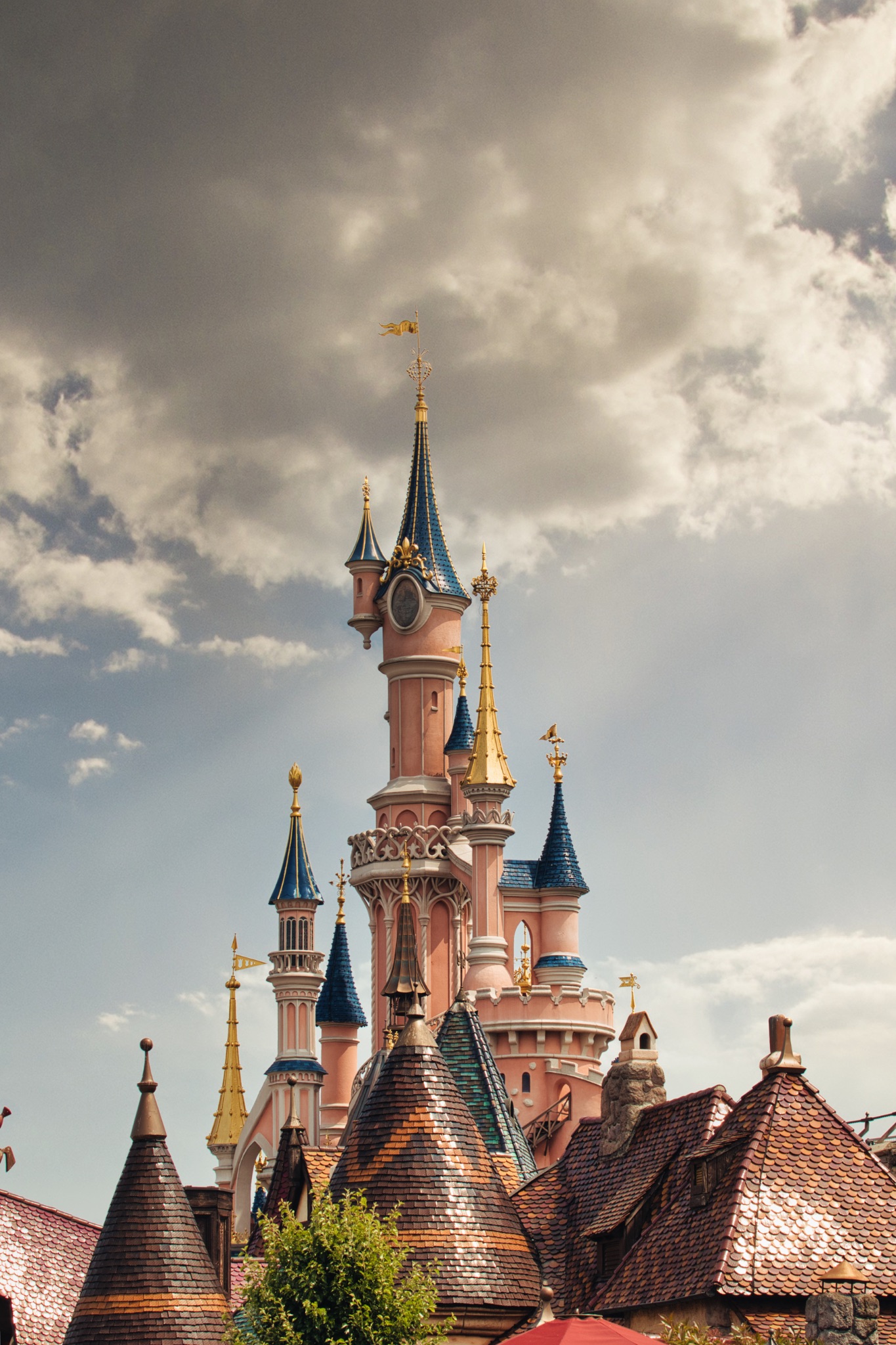 Castle with Pink Walls, Blue Spires, and Cloudy Sky at Disneyland Paris, France.