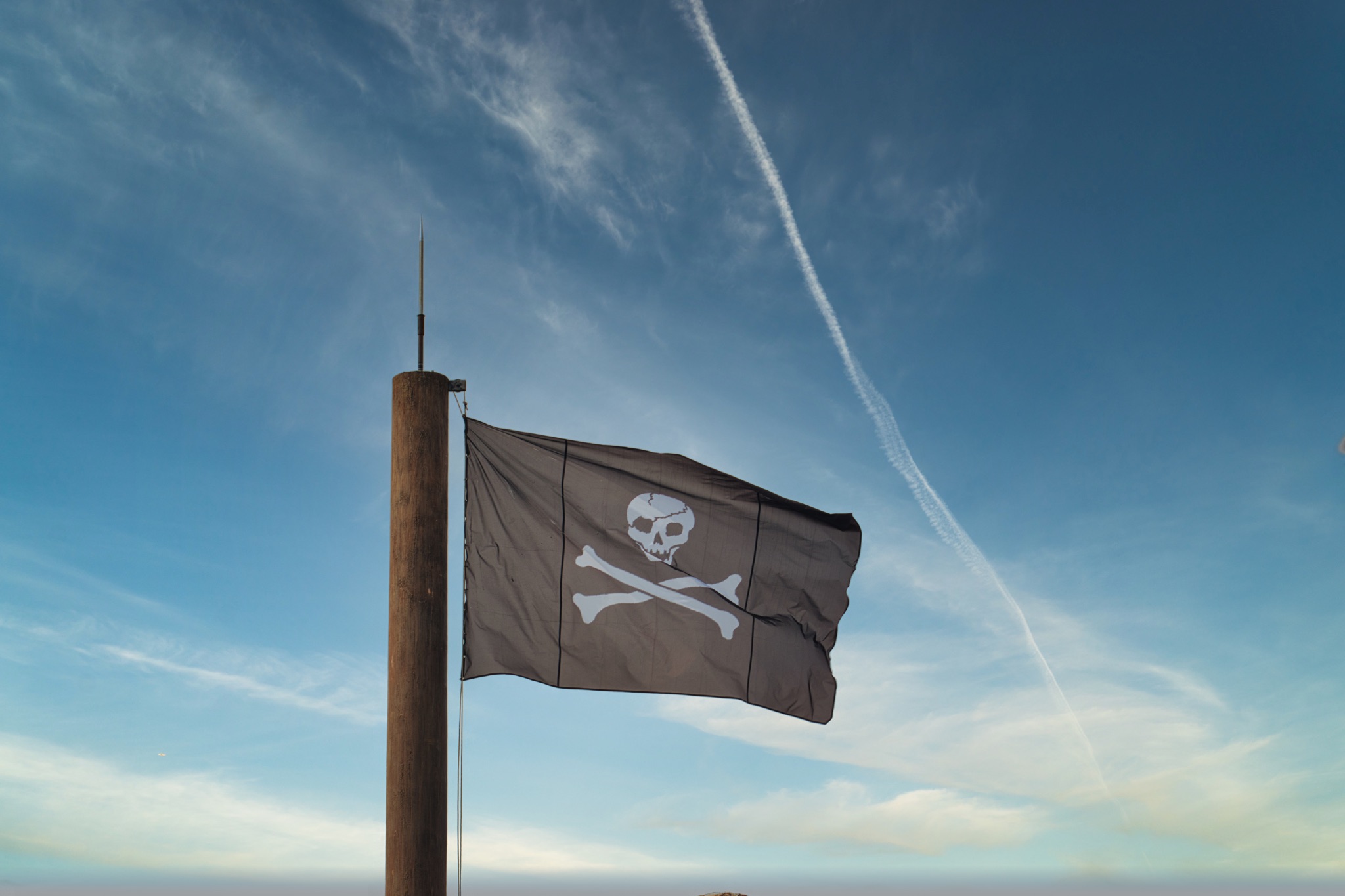 Pirate Flag on Pole Against Blue Sky at Disneyland Paris, France.