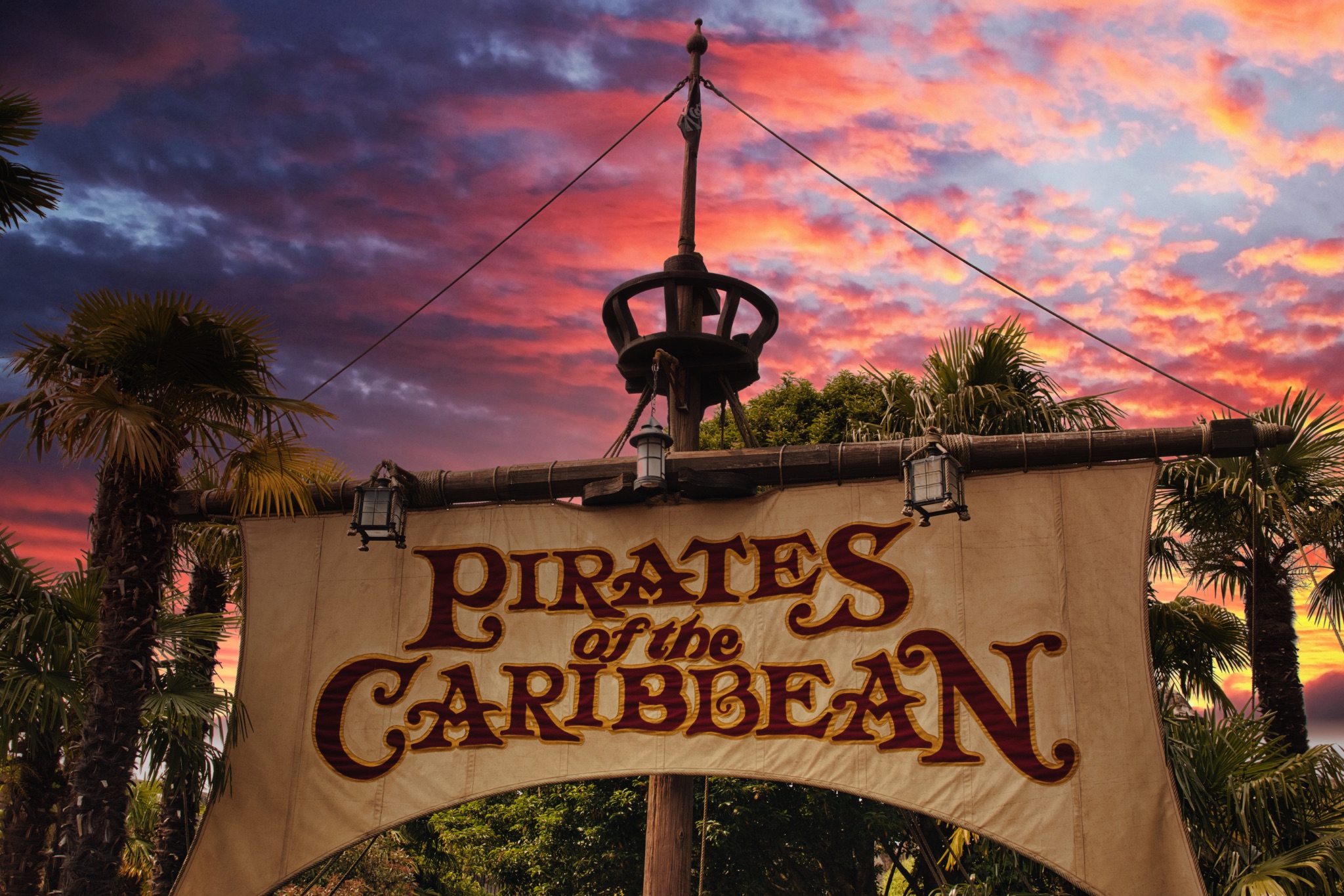 Pirates of the Caribbean Sign and Palm Trees with Sunset at Disneyland Paris, France.