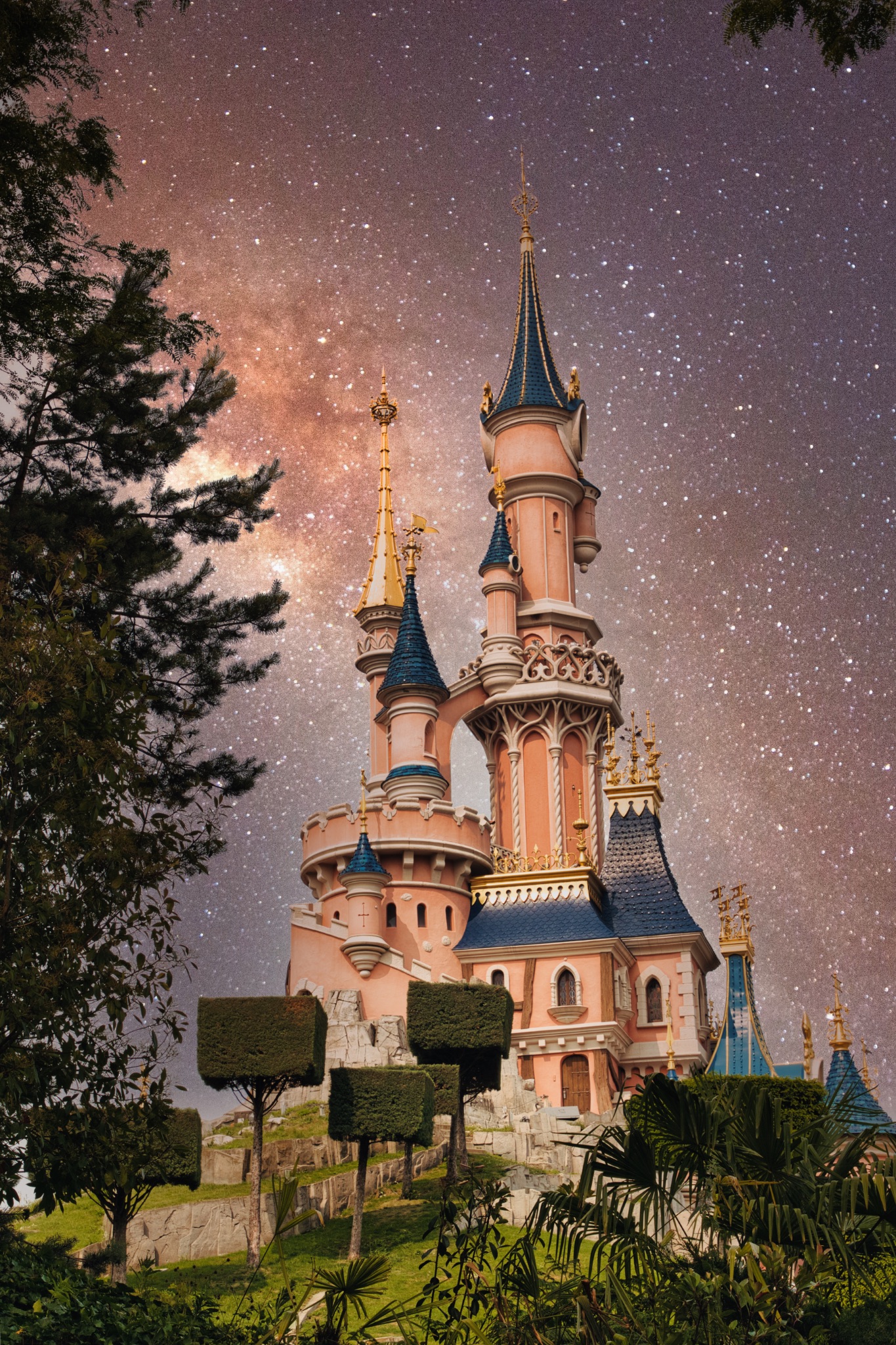 Pink Castle with Towers Against Starry Night Sky at Disneyland Paris, France.