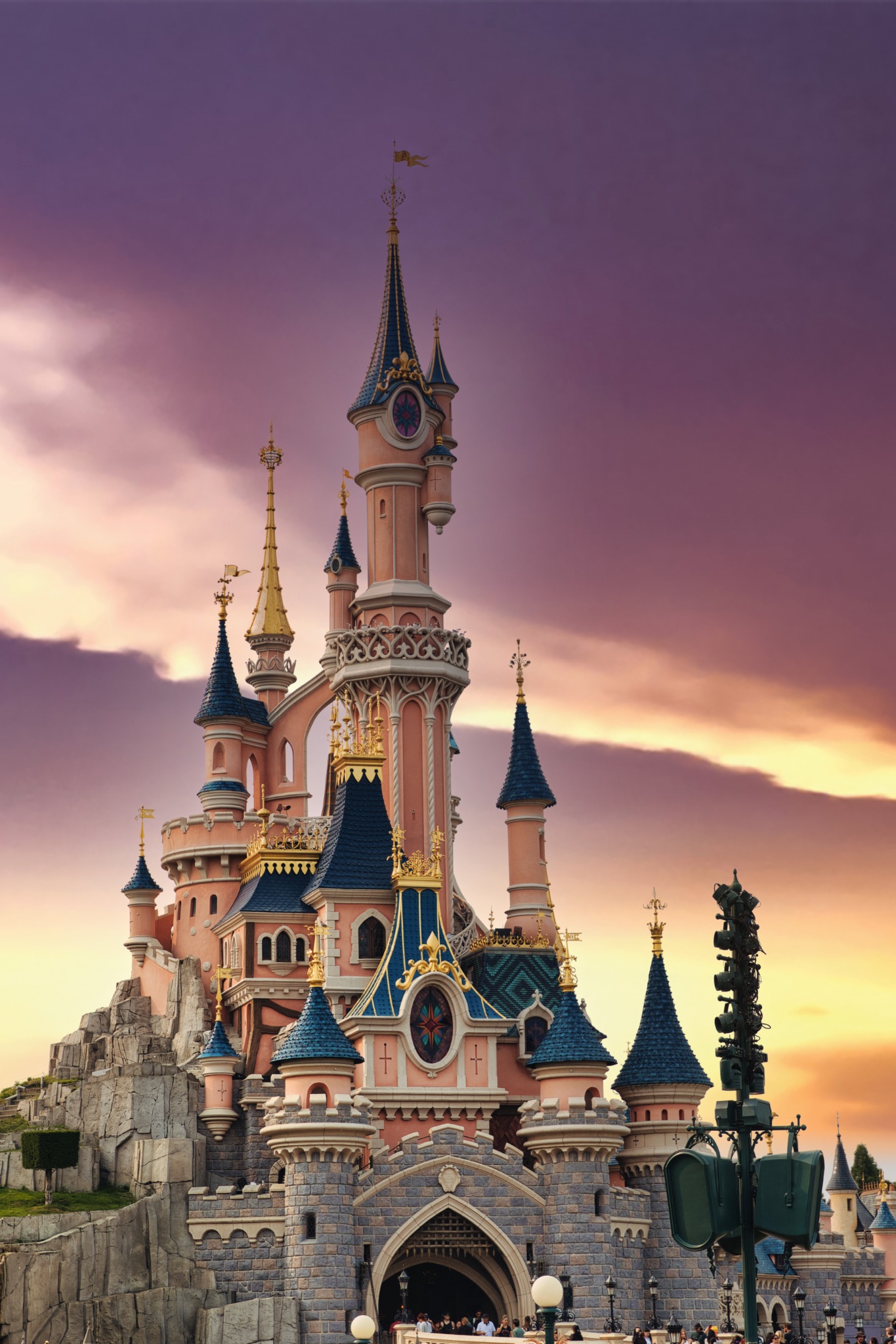 Pink Castle with Blue Roofs Against Sunset Sky at Disneyland Paris, France.