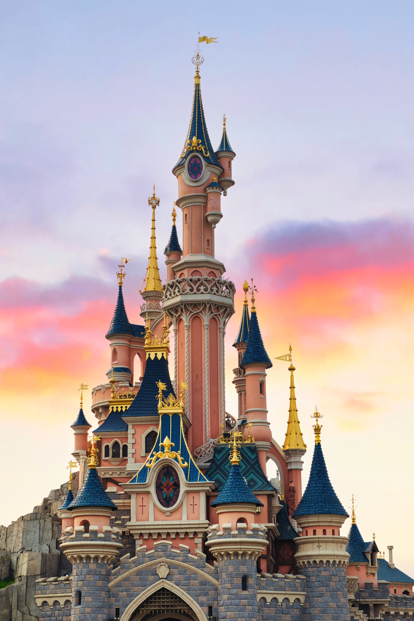 Pink Castle with Blue Turrets Under Sunset Sky at Disneyland Paris, France.
