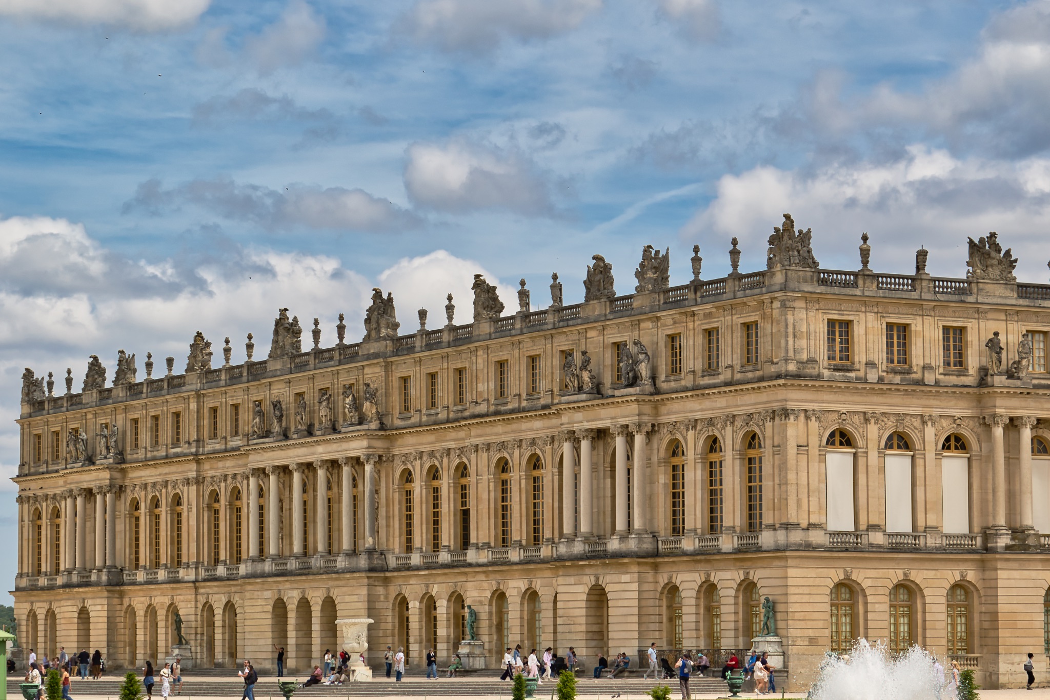 Palace of Versailles Exterior with Statues, Windows, and Visitors